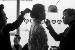 Black and white picture of makeup and hair being done on the bride