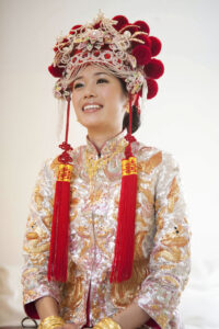 Bride wearing traditional Chinese headdress and wedding attire looking radiant and smiling