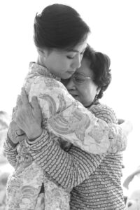 Black and white photo of bride and female relative in a loving embrace, a tear rolling down the brides cheek