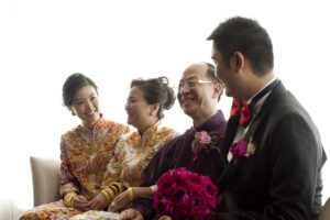 Bride sitting on a chair with family smiling