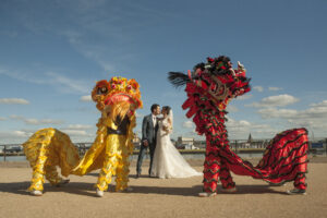 Yellow and red Chinese dragons either side of kissing bride and groom