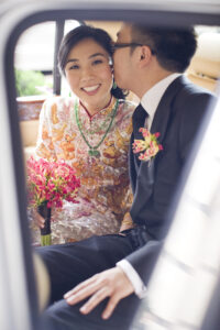 Groom kissing bride on the cheek in the back of a car