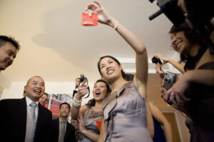 Bridesmaid holding up a red envelope surrounded by wedding guests