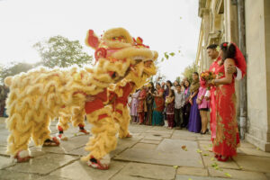 Gold Chinese dragons and wedding guests greet the bride and groom