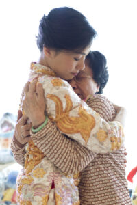 Bride with a delicate tear rolling down her cheek embracing her mother