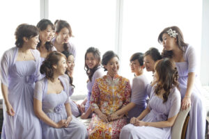 Bride in a traditional Chinese wedding dress with her bridesmaids in lilac Western dresses