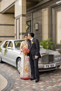 Silver Bentley behind a groom kissing his bride after the Chinese Tea Ceremony