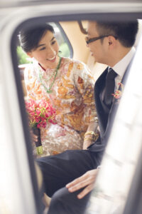 Bride and groom stealing a glance sitting in a silver Bentley