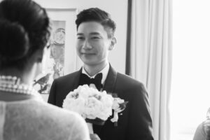 black and white image of smiling man in suit looking at a bride