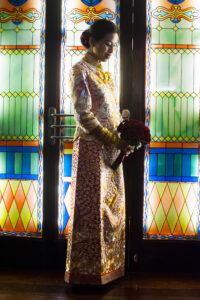 Bride looking at her flowers standing in front of a stained glass window