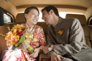 Bride and groom in the back of a car sharing whispers