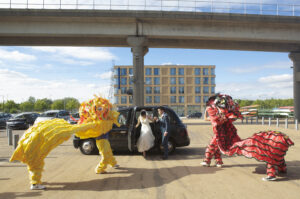 Bride and groom exiting a London cab with gold and red Chinese dragons greeting them